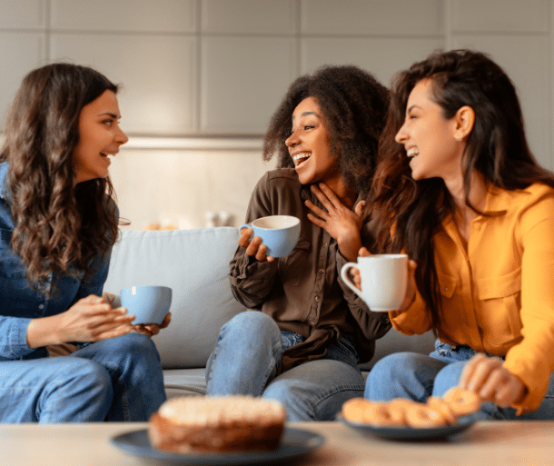 Three friends sharing coffee and conversation, representing meaningful connections and deeper friendships as we age